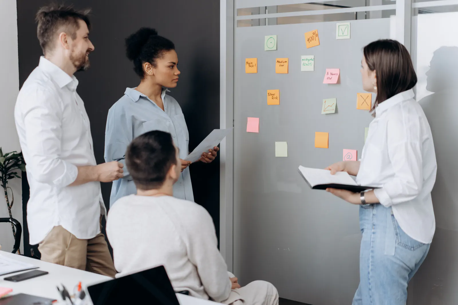 Eine Arbeitsgruppe bespricht gemeinsam Notizen an einer Arbeitswand